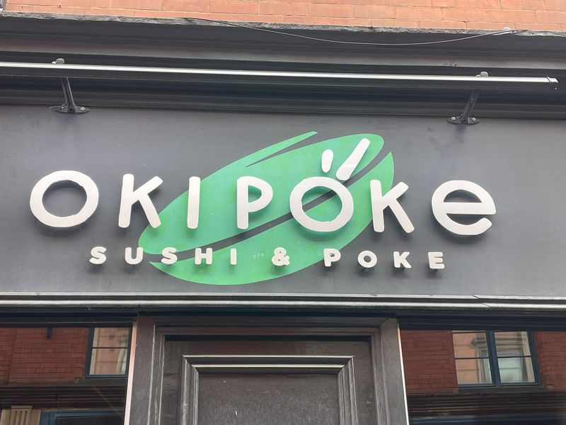 The Oki Poke sign at 50 St Andrew's Street: white rounded letters on a green leaf